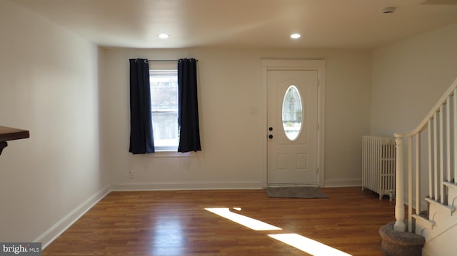 entryway with dark hardwood / wood-style floors and radiator heating unit