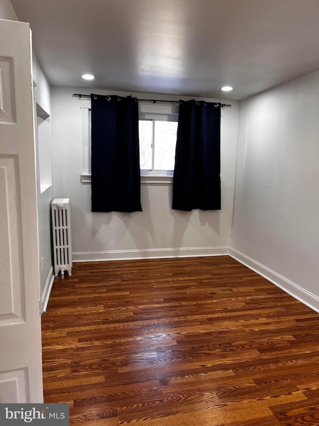 empty room featuring radiator and dark wood-type flooring