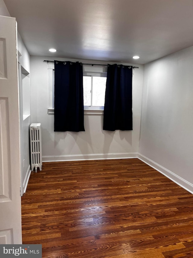 unfurnished room with radiator and dark wood-type flooring