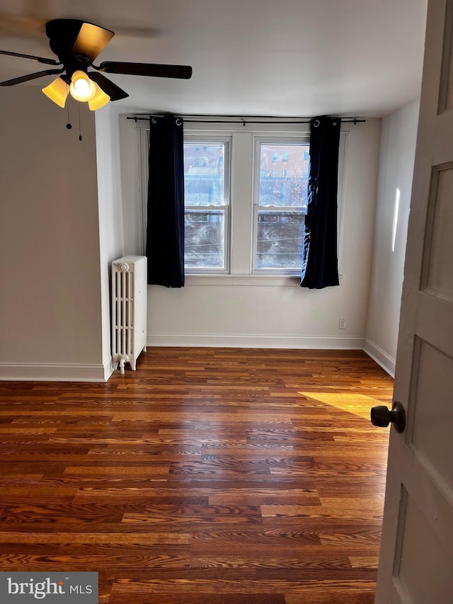 spare room featuring dark wood-type flooring, radiator heating unit, and ceiling fan