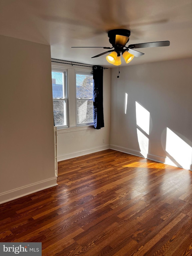 empty room with dark wood-type flooring and ceiling fan