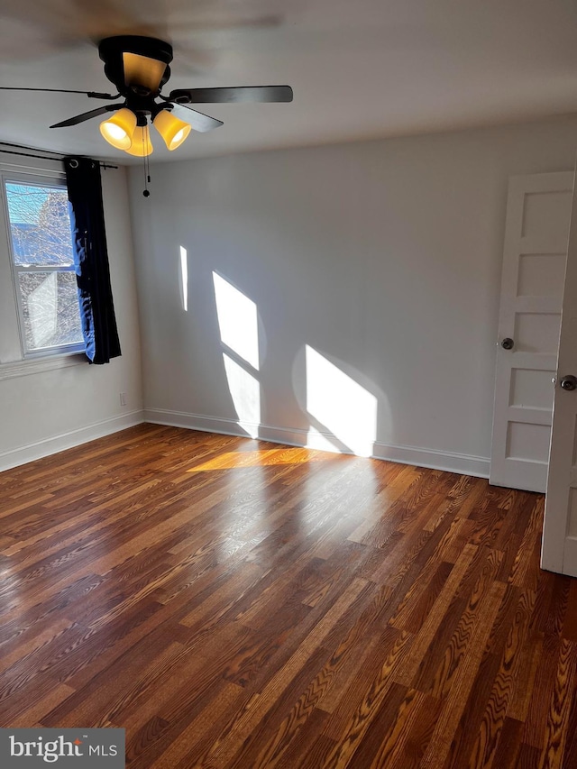 unfurnished room featuring dark wood-type flooring and ceiling fan