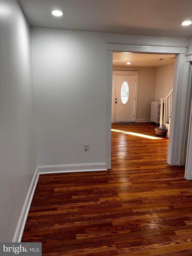 foyer entrance with dark hardwood / wood-style flooring and radiator heating unit