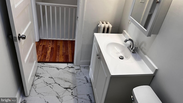 bathroom with vanity, radiator, and toilet