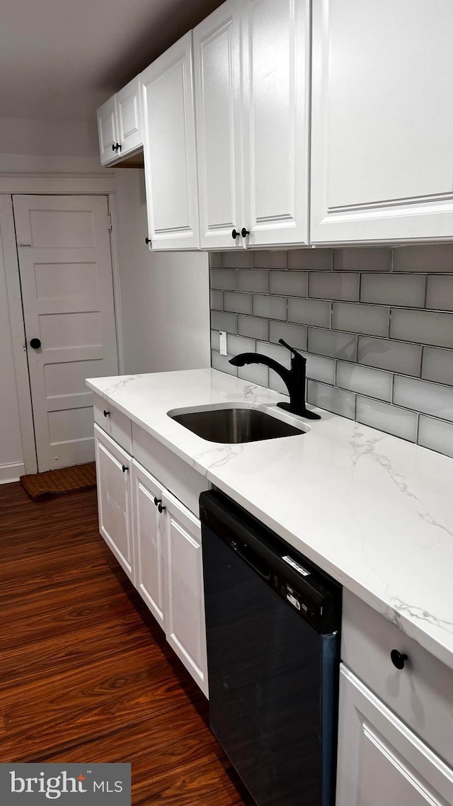 kitchen with black dishwasher, sink, white cabinets, light stone countertops, and dark wood-type flooring