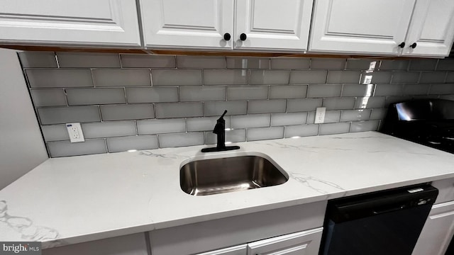 kitchen featuring black dishwasher, sink, decorative backsplash, and white cabinets