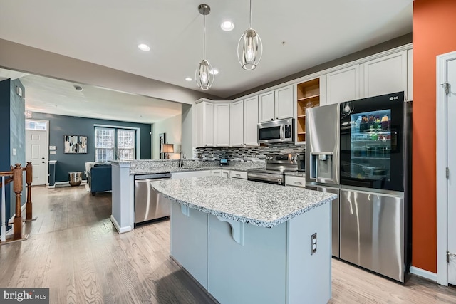 kitchen featuring a kitchen bar, decorative light fixtures, kitchen peninsula, stainless steel appliances, and white cabinets