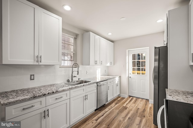 kitchen with stainless steel appliances, sink, white cabinets, and decorative backsplash