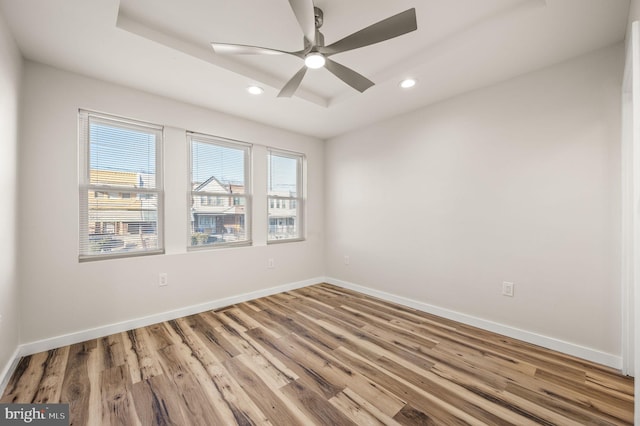 empty room featuring hardwood / wood-style flooring, plenty of natural light, and a tray ceiling