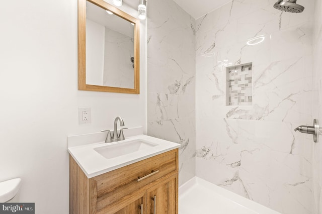 bathroom with vanity, toilet, and a tile shower