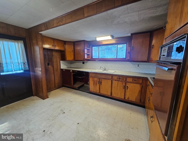 kitchen featuring sink, wooden walls, and wall oven