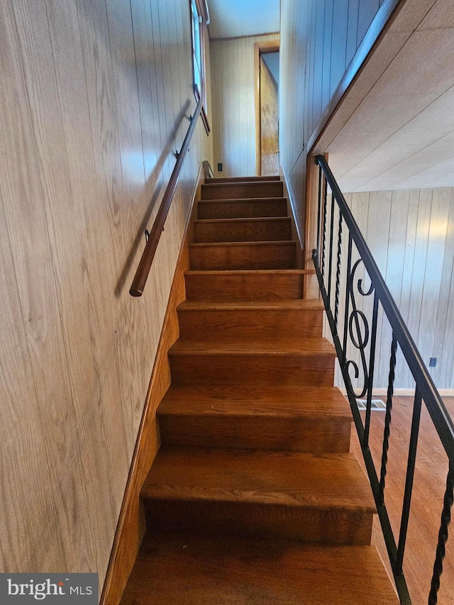 staircase featuring wooden walls