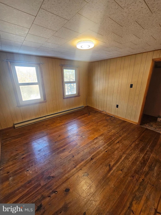 unfurnished room featuring a baseboard radiator, dark hardwood / wood-style flooring, and wood walls