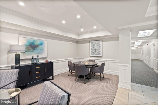 tiled dining area with ornamental molding, a raised ceiling, and ornate columns