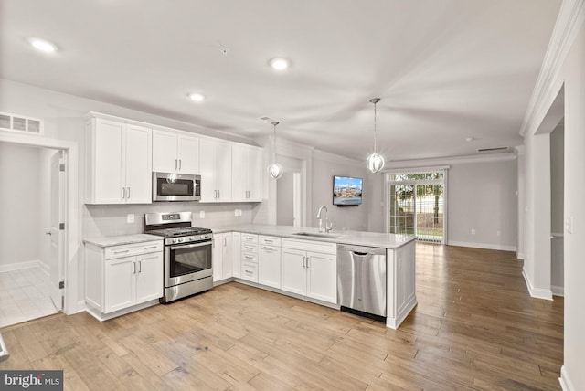 kitchen with sink, decorative light fixtures, stainless steel appliances, and kitchen peninsula