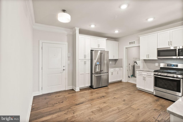 kitchen featuring backsplash, stainless steel appliances, white cabinets, and light wood-type flooring