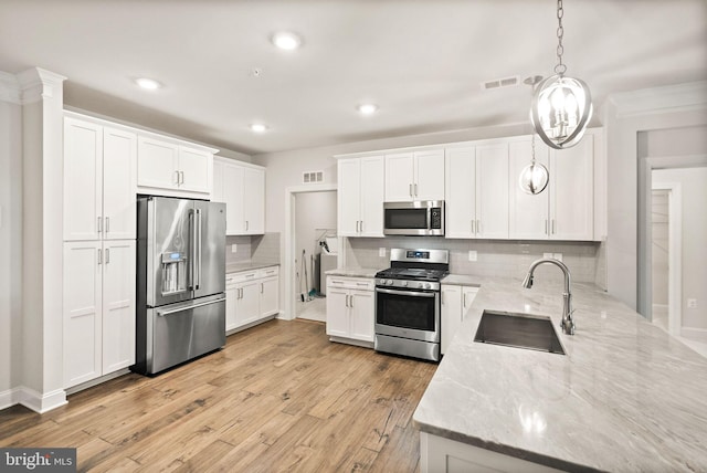 kitchen featuring hanging light fixtures, white cabinetry, appliances with stainless steel finishes, and sink