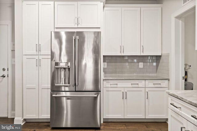 kitchen with light stone counters, backsplash, high end refrigerator, and white cabinets