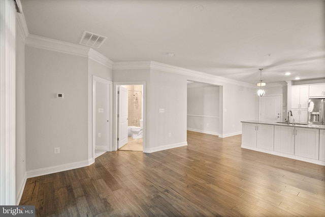 unfurnished living room featuring crown molding, sink, and hardwood / wood-style floors