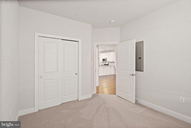 unfurnished bedroom featuring light carpet, electric panel, and a closet