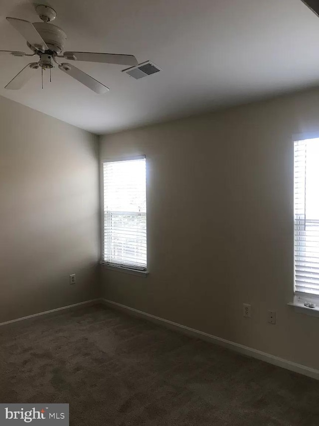 unfurnished room featuring ceiling fan, plenty of natural light, and dark carpet