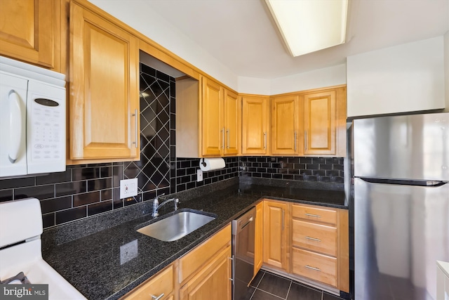 kitchen with sink, dark tile patterned floors, appliances with stainless steel finishes, backsplash, and dark stone counters