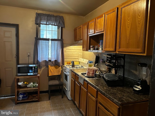 kitchen featuring dark stone countertops and white gas range oven