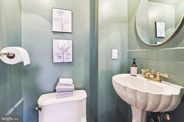 bathroom featuring sink, backsplash, and toilet