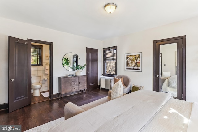 bedroom with connected bathroom, radiator heating unit, and dark hardwood / wood-style flooring