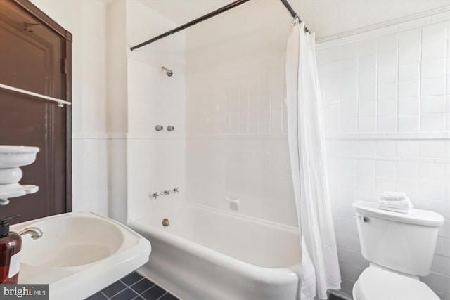 full bathroom with sink, tile walls, tile patterned floors, toilet, and shower / bath combo with shower curtain