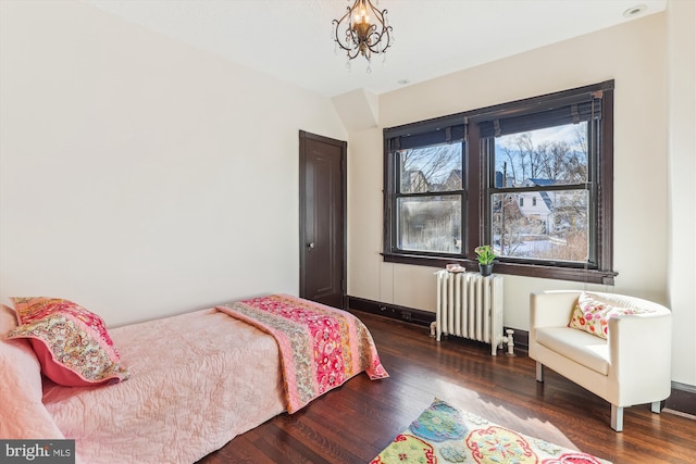 bedroom with an inviting chandelier, dark wood-type flooring, and radiator heating unit