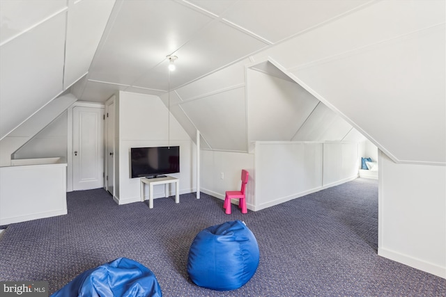 additional living space with vaulted ceiling and dark colored carpet