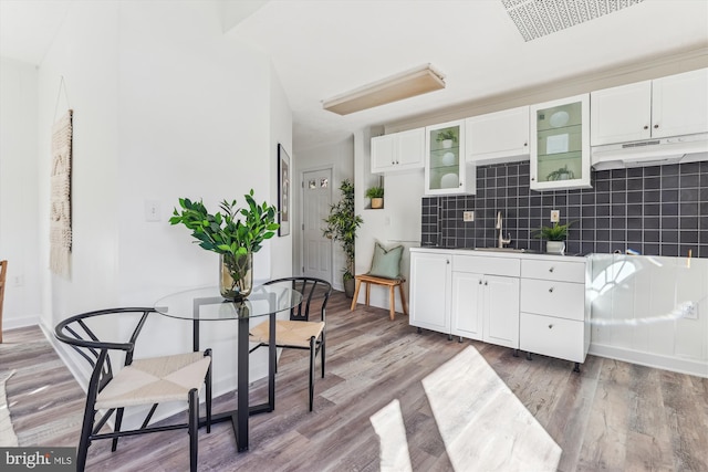 kitchen featuring white cabinetry, wood-type flooring, sink, and decorative backsplash