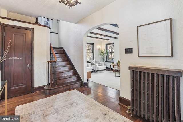 foyer with dark hardwood / wood-style flooring, beam ceiling, and a textured ceiling