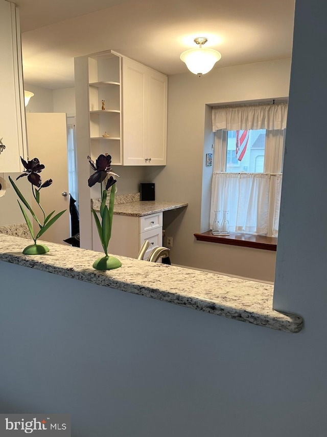 kitchen with open shelves, light stone countertops, and white cabinets