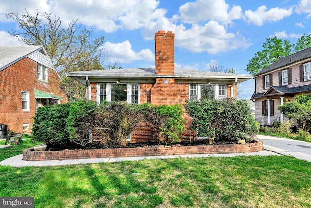 view of front of property with a chimney, brick siding, and a front lawn
