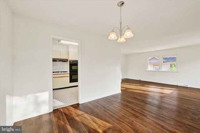 unfurnished room featuring a chandelier, dark wood-type flooring, and baseboards