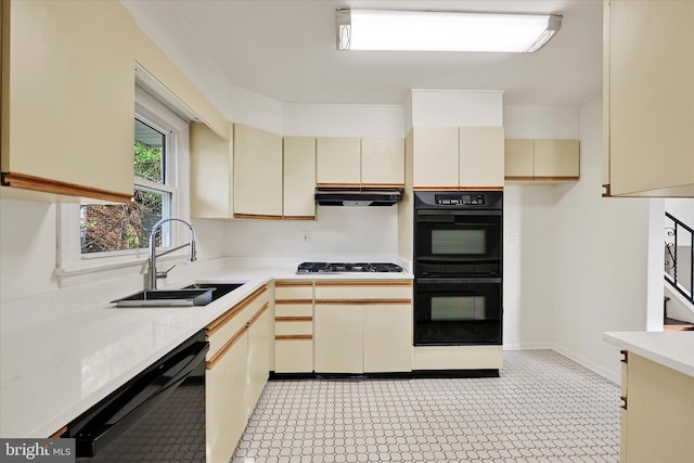 kitchen with black appliances, cream cabinetry, a sink, light countertops, and ventilation hood