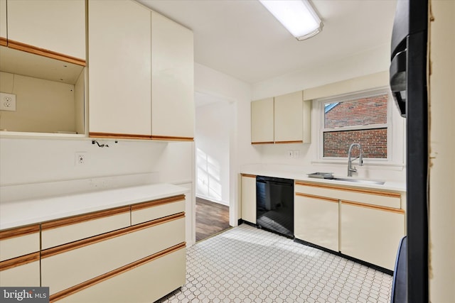 kitchen featuring a sink, dishwasher, cream cabinets, and light countertops