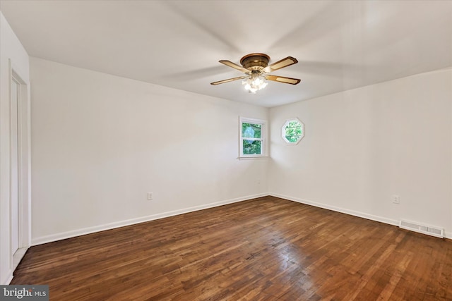 spare room with dark wood-type flooring, a ceiling fan, and baseboards
