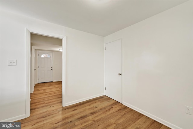 empty room with baseboards and light wood-type flooring