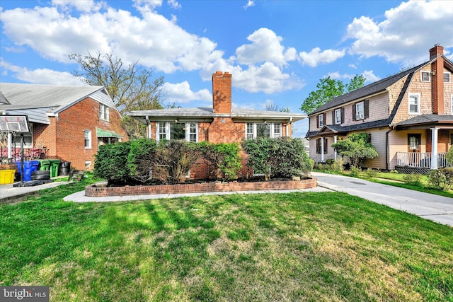 view of front of home with a chimney, a front yard, and brick siding