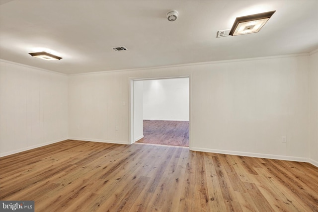 spare room with wood finished floors, crown molding, baseboards, and a smoke detector