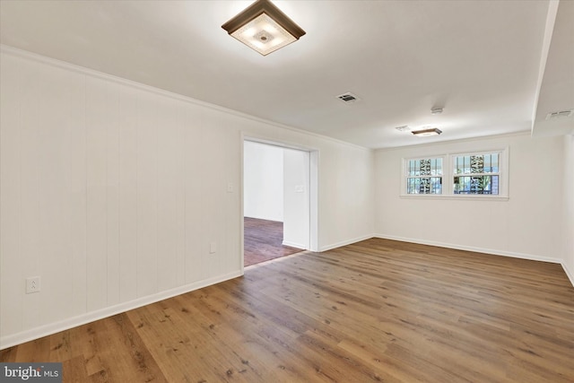 unfurnished room featuring wood finished floors, ornamental molding, and baseboards