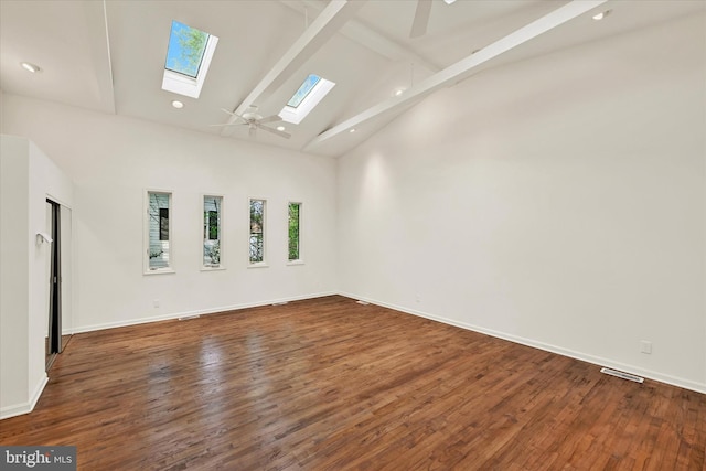 spare room with a skylight, beam ceiling, high vaulted ceiling, ceiling fan, and wood finished floors