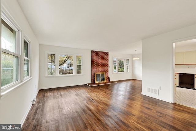 unfurnished living room featuring dark wood-style floors, a chandelier, baseboards, and a fireplace