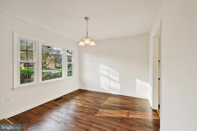 unfurnished room featuring a chandelier, dark wood-type flooring, and baseboards