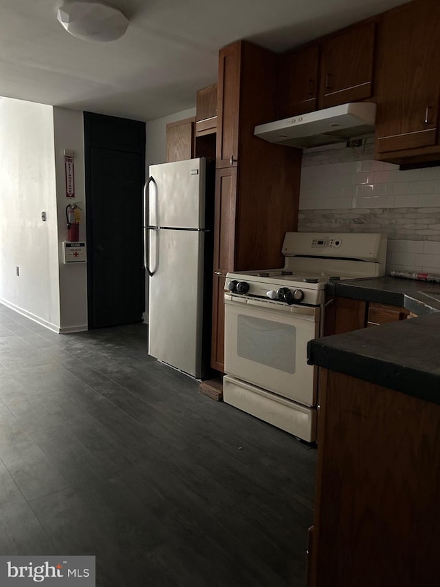 kitchen with stainless steel refrigerator, dark hardwood / wood-style floors, white gas stove, and tasteful backsplash