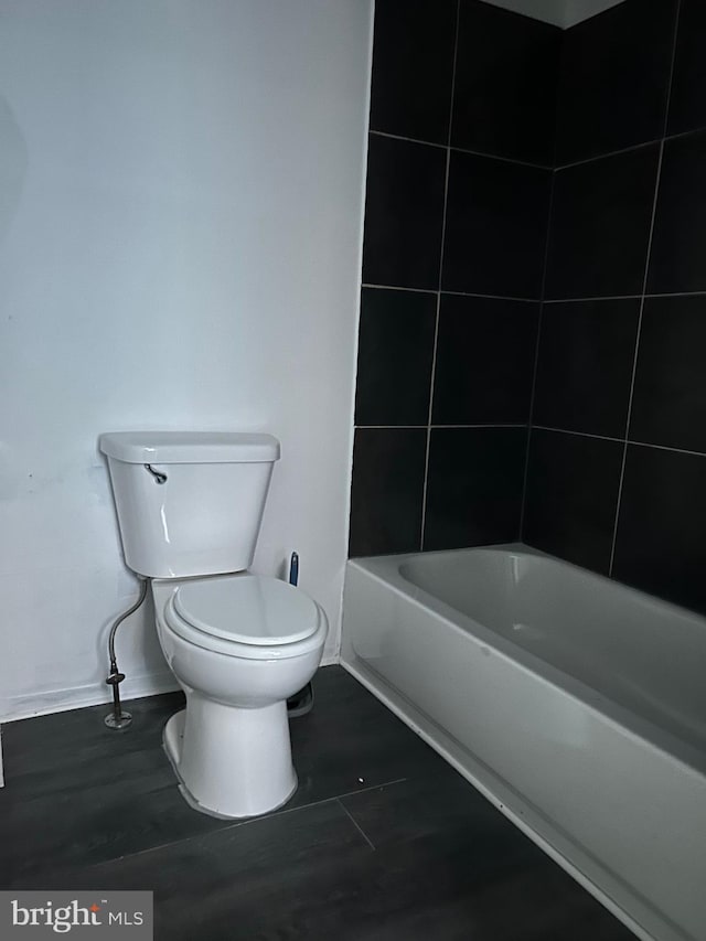 bathroom featuring tile patterned flooring, a bathing tub, and toilet