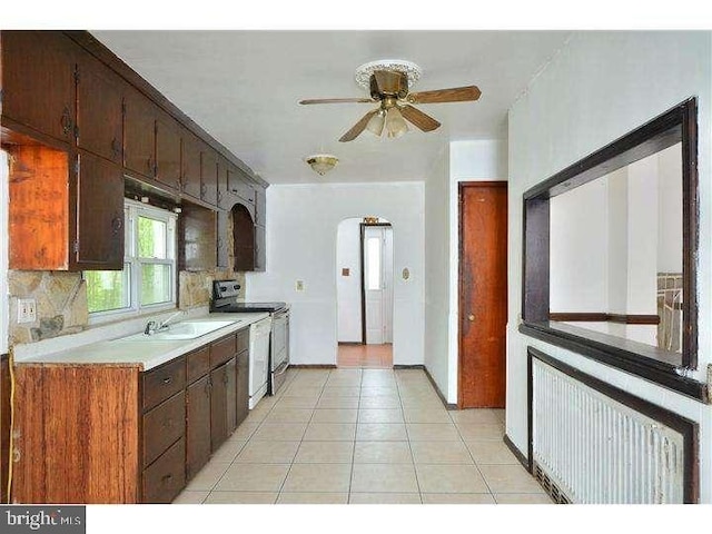 kitchen with radiator, stainless steel electric range, sink, ceiling fan, and decorative backsplash